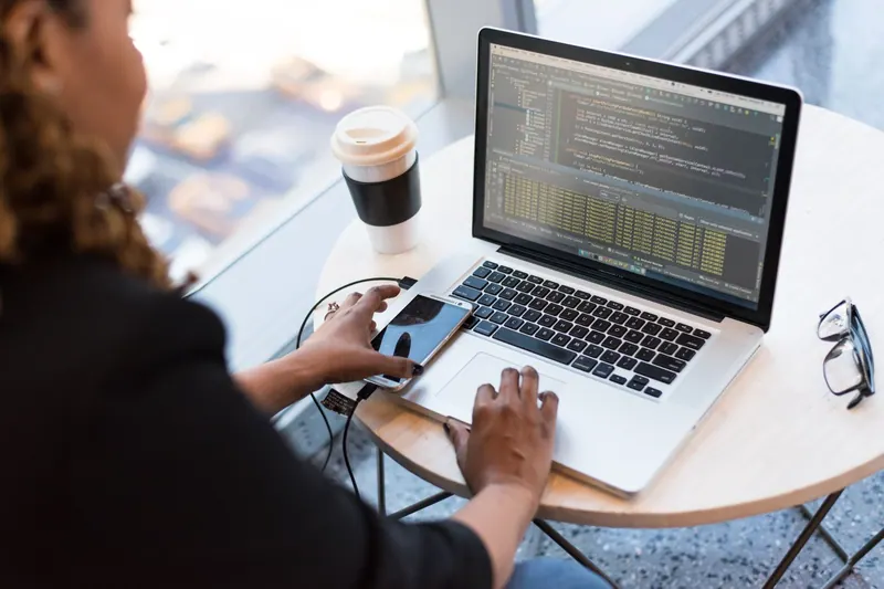 Person programmiert an einem Laptop mit Code auf dem Bildschirm