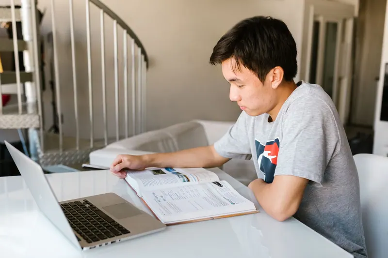 Studentin lernt mit Laptop und Notizbuch am Schreibtisch